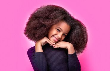 Laughing cute afro girl portrait. Cute multiracial small girl smiling, Isolated on a pink background. Smile little african american girl. African American girl smile and curly hair