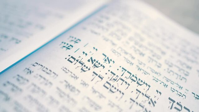 Close-up video recording of Hebrew words in the open Torah book. Prayer in Hebrew.