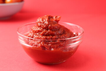 tomato paste in a glass sauce bowl on a red background monocolor. Food sauce red tomato food