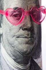 Benjamin Franklin from US 100 dollar banknote in pink heart sunglasses