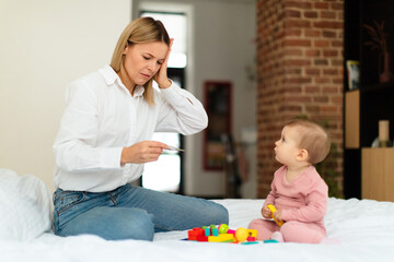 Babies and fever. Shocked mother measuring kid's temperature with thermometer, caring for ill daughter, sitting on bed