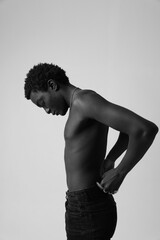 Fototapeta premium Black and white portrait of confident man shirtless posing indoor. Vertical.