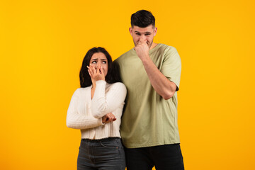 Sad dissatisfied young arabic woman and guy in casual cover nose with fingers, suffer from bad smell