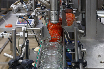 Empty jars for salmon red caviar in packaging line.