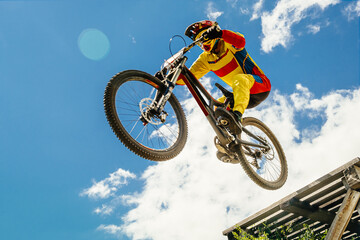 Fototapeta na wymiar cyclist drops downhill in bokeh background blue sky