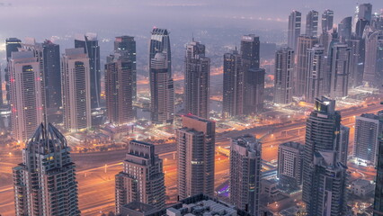 JLT skyscrapers and marina towers near Sheikh Zayed Road aerial night to day . Residential buildings