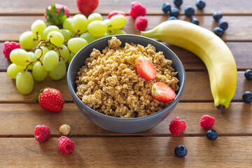 Plate with homemade granola and various fruits for cooking tasty and healthy breakfast on wooden...