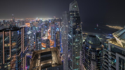 Panorama showing JBR district and Dubai Marina with JLT. Traffic between skyscrapers aerial night .