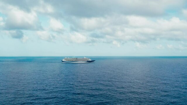 Dolly shot on large passenger cruise ship with tourist on board, alone in sea at dramatic overcast weather with clouds and blue sky. Idyllic scenery