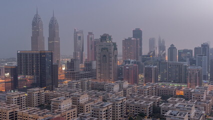 Fototapeta na wymiar Skyscrapers in Barsha Heights district and low rise buildings in Greens district aerial night to day .