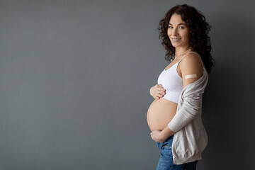 Smiling Pregnant Woman Showing Arm With Adhesive Bandage After Vaccine Injection Shot