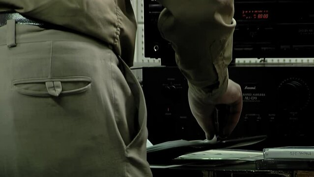 Sound Engineer Choosing Compact Discs or DVDs Stored in Sleeves in a File in His Studio. Close Up.