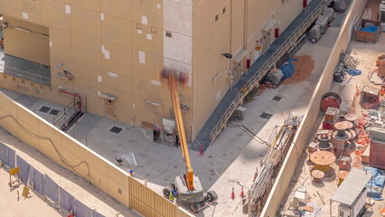 Construction workers in bucket of crane vehicle for restore and repair of the facade of building aerial .