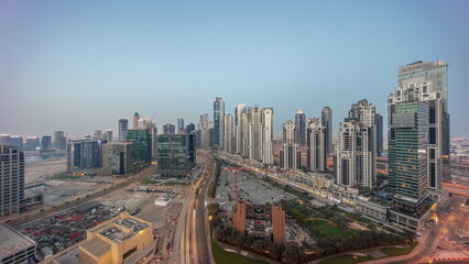 Naklejka premium Bay Avenue with modern towers residential development in Business Bay aerial panoramic night to day , Dubai