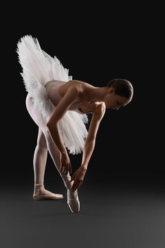 Young ballerina practicing dance moves on black background © New Africa