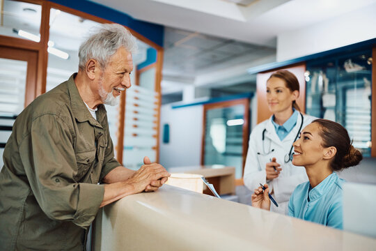 Happy senior man talks to nurse while checking in at doctor's office.