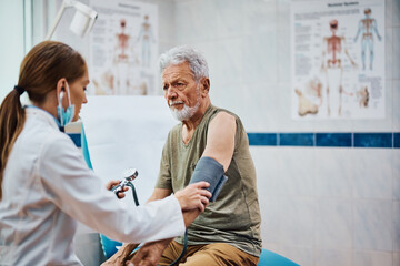 Senior man getting his blood pressure checked during medical examination in hospital. © Drazen