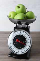 Kitchen scale with green apples on wooden table