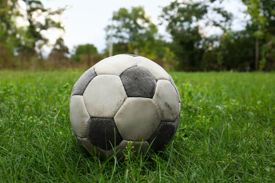 Dirty soccer ball on fresh green grass outdoors