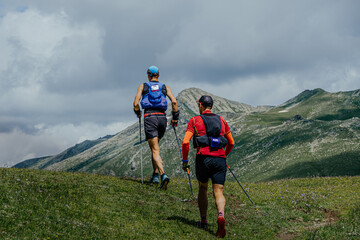 two athletes walk mountain trail during marathon