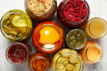 Many jars with different preserved products on white table, flat lay
