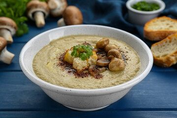 Delicious cream soup with mushrooms and croutons on blue wooden table