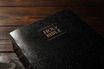 Bible with black cover on wooden table, closeup. Christian religious book