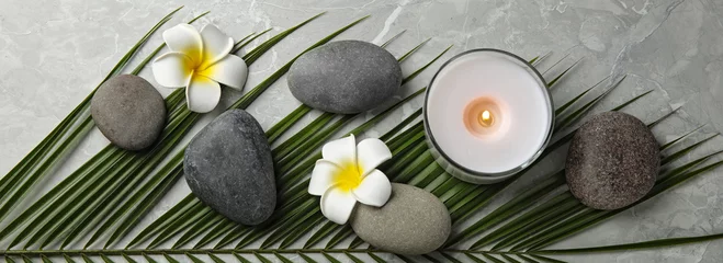 Poster Spa treatment. Flat lay composition with stones, plumeria flowers and burning candle on grey table. Banner design © New Africa