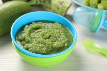 Healthy baby food. Bowl with tasty broccoli puree on white wooden table, closeup