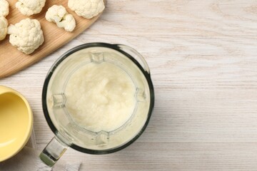 Baby food. Blender with delicious cauliflower puree on light wooden table, flat lay and space for...