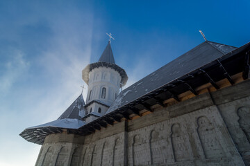 Fototapeta na wymiar Monastery church in the snow. Carpathian mountain village in Transylvania, Romania
