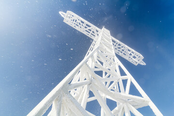 Frosty metal cross, contrasting with the blue sky