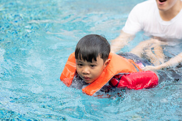 Fototapeta na wymiar Father teaching son to swim at swimming pool. family outdoor activity on holiday in summer weather