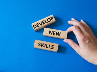 Develop New skills symbol. Concept word Develop New skills on wooden blocks. Businessman hand. Beautiful blue background. Business and Develop New skills concept. Copy space
