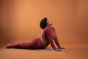 body positive curvy black girl wearing sportswear in studio doing yoga and exercising