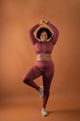 body positive curvy black girl wearing sportswear in studio doing yoga and exercising
