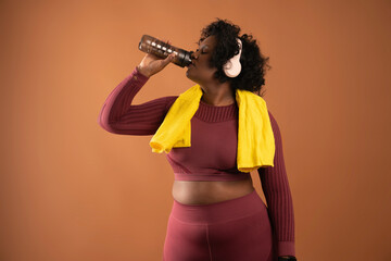 body positive curvy black girl wearing sportswear drinking water