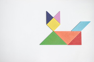 color tangram puzzle in cat shape on wood background