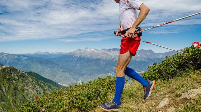 male athlete running mountain marathon with trekking poles
