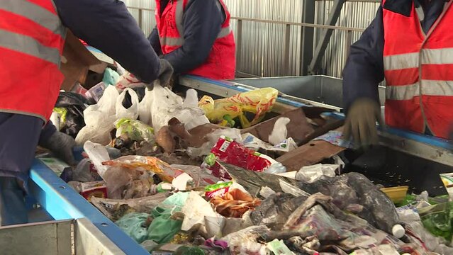 Workers sort garbage at a waste recycling plant