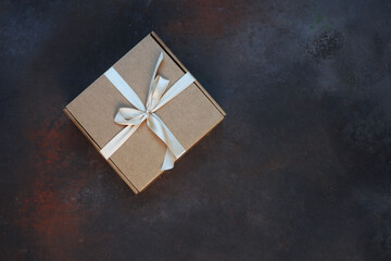 The cardboard holiday box is tied with a ribbon. Festive packaging. A gift for the holiday. With space to copy.View from above.Dark background.