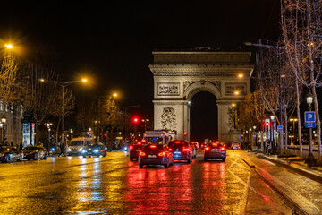 A nighttime view looking up the Champs-Élysées towards The Arc de Triomphe, a famous landmark in...