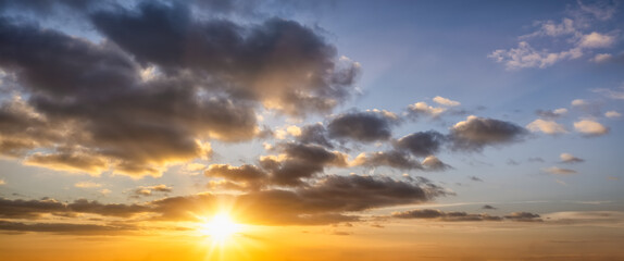 A sunset sky with orange and dark stormy clouds as a background or texture