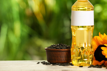 Sunflower cooking oil, seeds and yellow flowers on white wooden table outdoors. Space for text