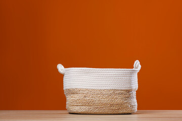 Empty wicker laundry basket near brown wall