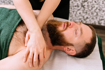 Fototapeta na wymiar Bearded man receiving complex facial and chest massage in beauty salon.Beauty and skincare concept with a man. Middle aged male relaxed with massage for facial lifting 