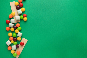 Different tasty chewing gums on green background, flat lay. Space for text