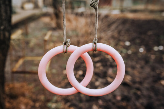 Homemade round plastic rings hanging on a rope outdoors for sports, gymnastics. Close-up photo, children's entertainment concept.