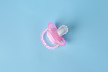 One new baby pacifier on light blue background, top view