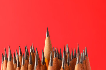 Sharp graphite pencils on red background, space for text